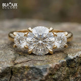 Oval-Cut Center Diamond with Flanking Round Accent Stones Set in a Timeless Yellow Gold Band - Bijoux Eclore