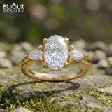 Oval-Cut Center Diamond with Sparkling Trilliant Side Stones Set in a Luxurious Yellow Gold Band - Bijoux Eclore